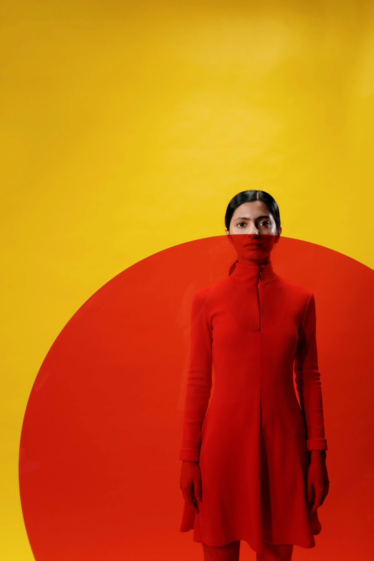 Model in a red zip-neck dress, seen against a yellow backdrop with a large red circle, by cottonbro studio.