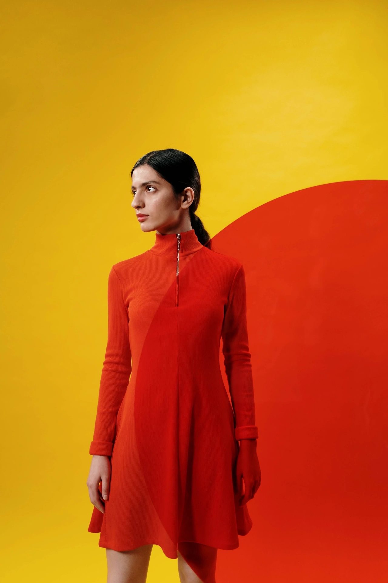 Model in a red zip-neck dress against a yellow backdrop with a red circle, by cottonbro studio.
